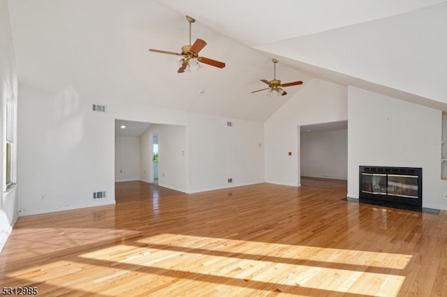 unfurnished living room with heating unit, ceiling fan, high vaulted ceiling, and light hardwood / wood-style floors