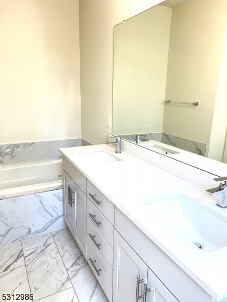 bathroom with tiled tub and vanity