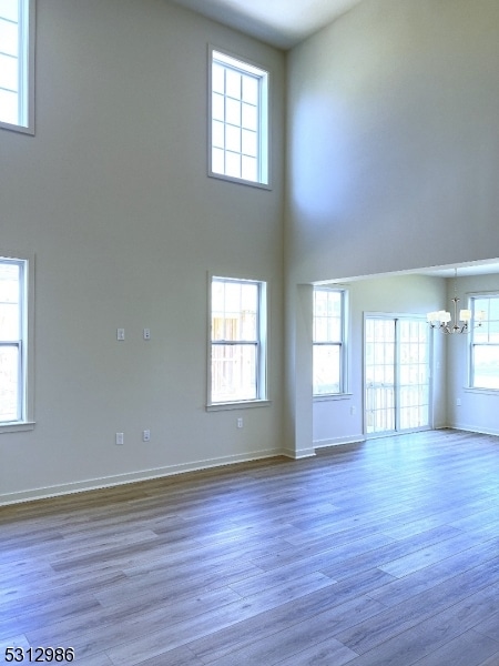 unfurnished living room featuring wood-type flooring, a high ceiling, and a wealth of natural light