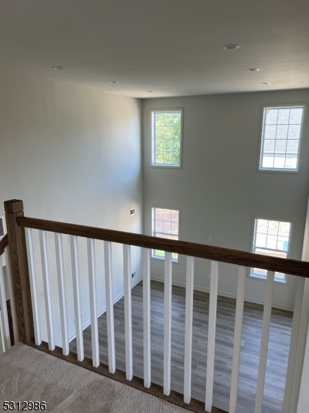 stairway with wood-type flooring and a healthy amount of sunlight