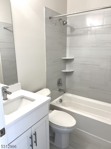 full bathroom featuring tiled shower / bath combo, vanity, and toilet