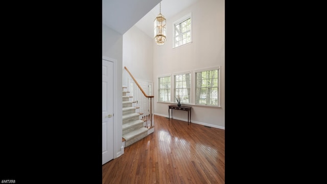 foyer with a towering ceiling, an inviting chandelier, and dark wood-type flooring