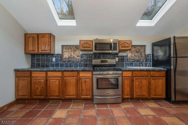 kitchen with tile patterned floors, decorative backsplash, plenty of natural light, and stainless steel appliances