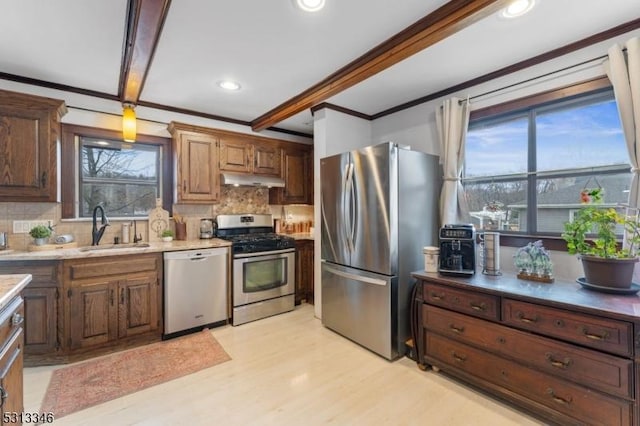 kitchen featuring decorative backsplash, a sink, stainless steel appliances, ornamental molding, and a wealth of natural light