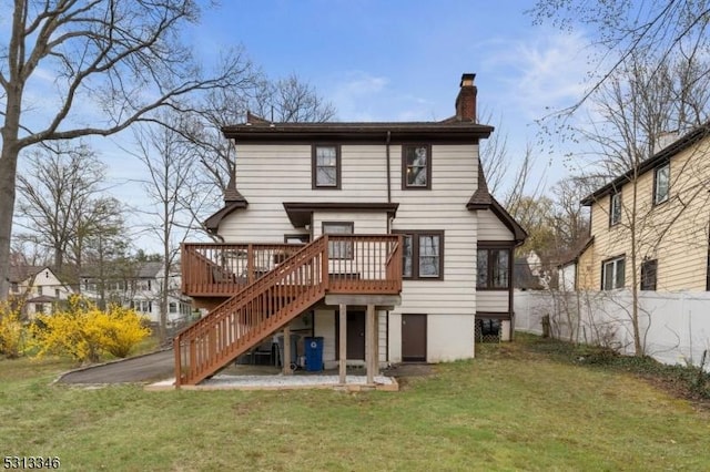 back of property featuring a chimney, stairway, fence, a wooden deck, and a lawn