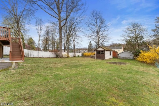 view of yard featuring stairway, an outdoor structure, a shed, a deck, and fence