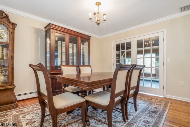 dining room featuring light wood-type flooring, ornamental molding, a baseboard heating unit, and a notable chandelier