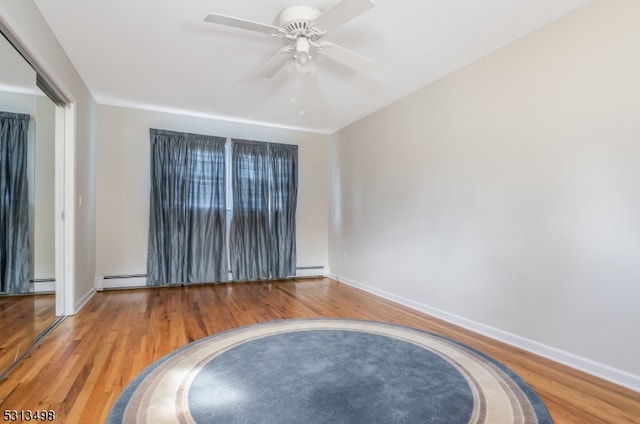 unfurnished room with wood-type flooring, baseboard heating, and ceiling fan