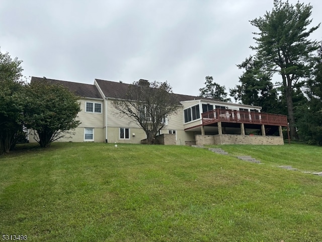 rear view of house featuring a wooden deck and a yard