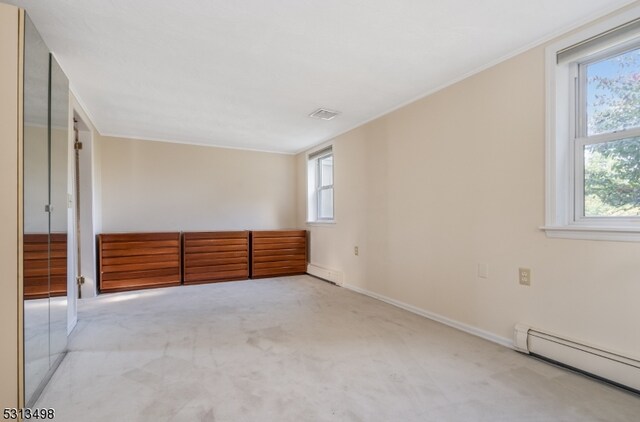 carpeted empty room with a baseboard heating unit, a healthy amount of sunlight, and crown molding