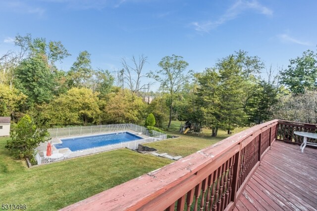 view of pool with a wooden deck and a yard