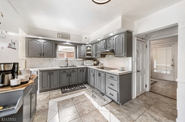 kitchen featuring gray cabinets, backsplash, light tile patterned floors, and sink