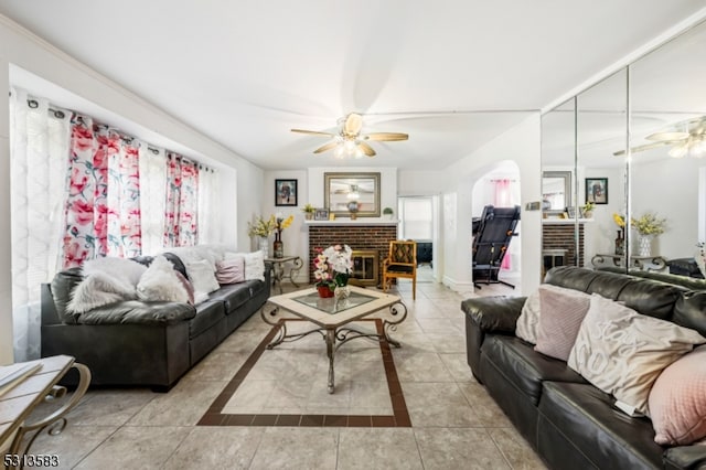 tiled living room with a fireplace and ceiling fan