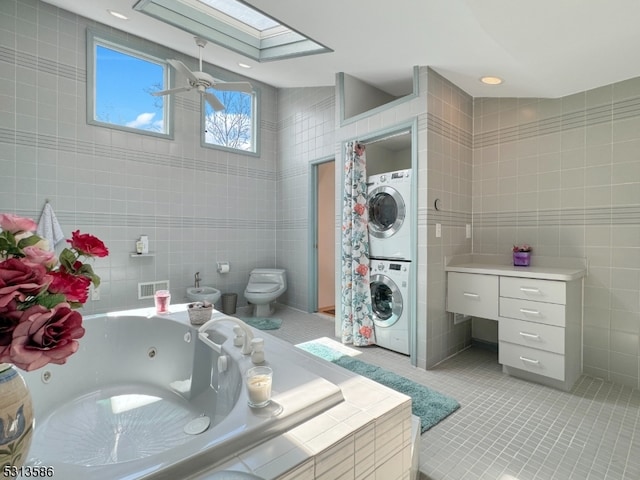 bathroom with stacked washer and clothes dryer, tile walls, and a tub