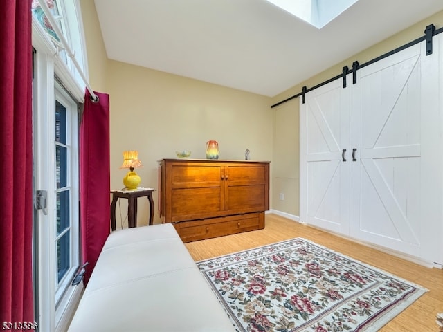 bedroom featuring light hardwood / wood-style floors, a skylight, and a barn door