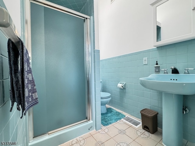 bathroom featuring tile walls, tile patterned flooring, a shower with door, and toilet