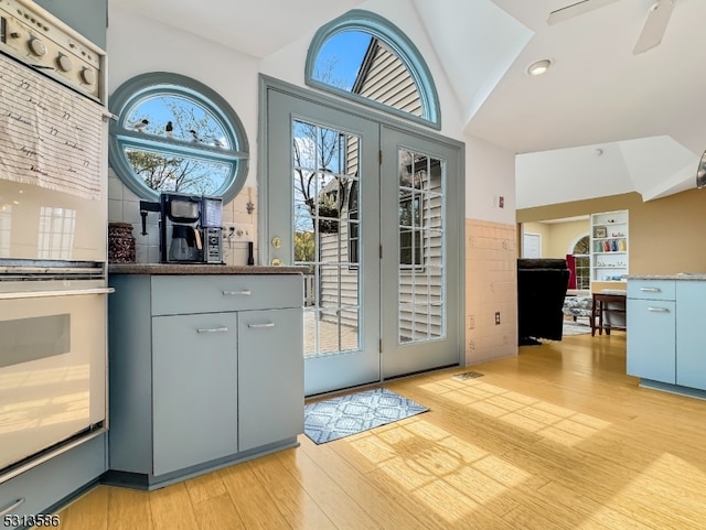 interior space with lofted ceiling, double oven, ceiling fan, and light hardwood / wood-style flooring