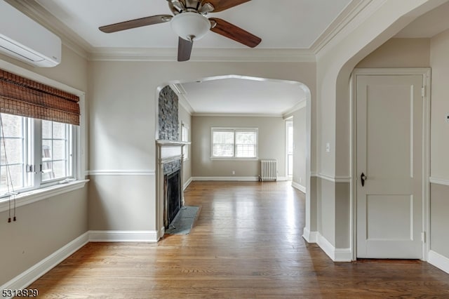 interior space with radiator heating unit, ornamental molding, hardwood / wood-style floors, and a wall mounted AC