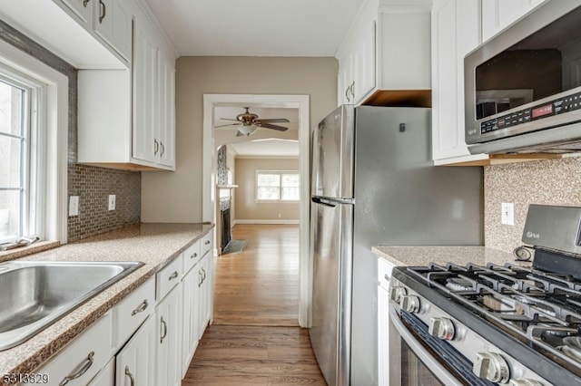 kitchen featuring light hardwood / wood-style floors, tasteful backsplash, white cabinets, stainless steel appliances, and ceiling fan