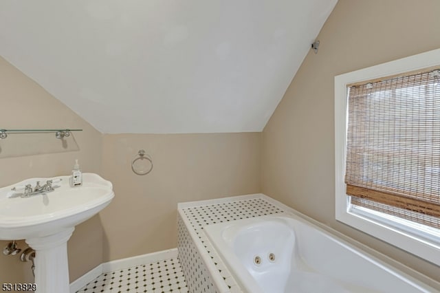 bathroom with a tub to relax in and vaulted ceiling