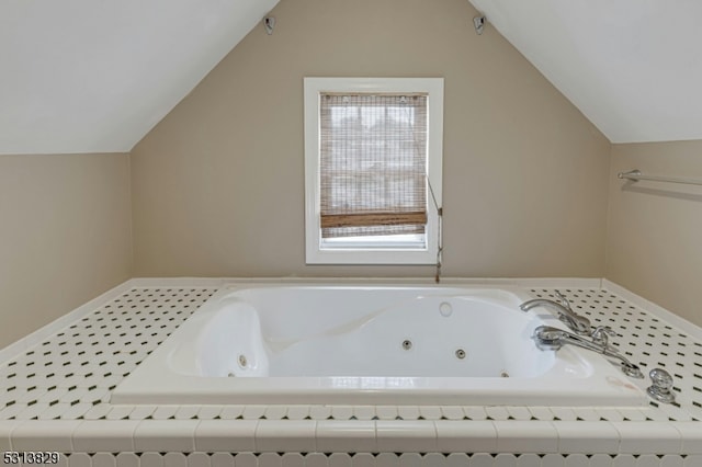 bathroom featuring tiled tub and lofted ceiling