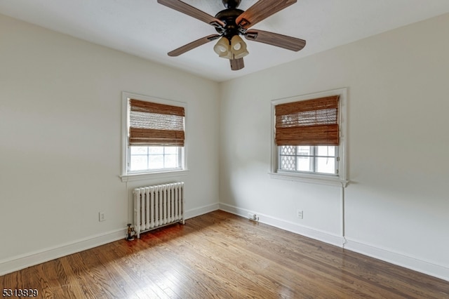 unfurnished room featuring ceiling fan, hardwood / wood-style flooring, radiator heating unit, and a wealth of natural light