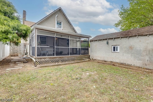 rear view of house featuring a lawn and a sunroom