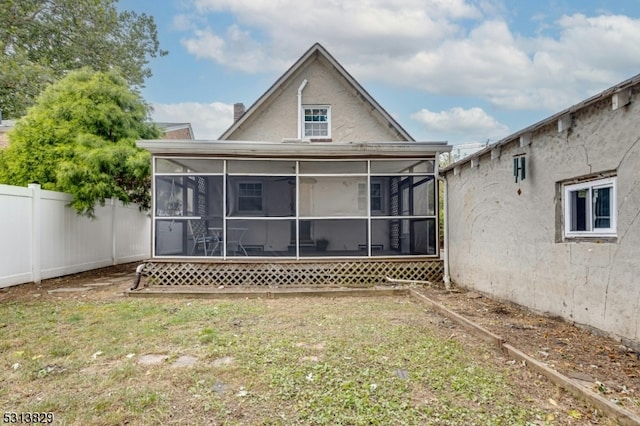 rear view of property featuring a yard and a sunroom