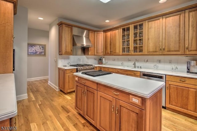 kitchen featuring a center island, dishwasher, light hardwood / wood-style floors, wall chimney exhaust hood, and tasteful backsplash