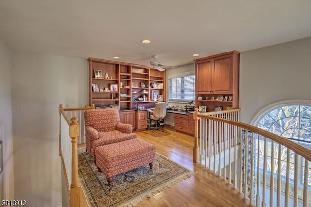 sitting room featuring ceiling fan, light hardwood / wood-style floors, and built in desk