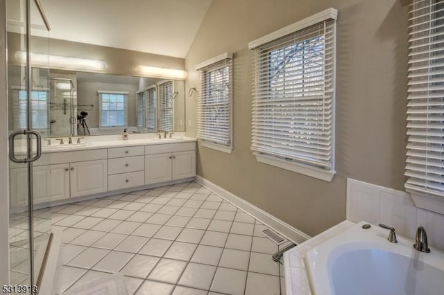 bathroom with a healthy amount of sunlight, vaulted ceiling, tile patterned flooring, and vanity