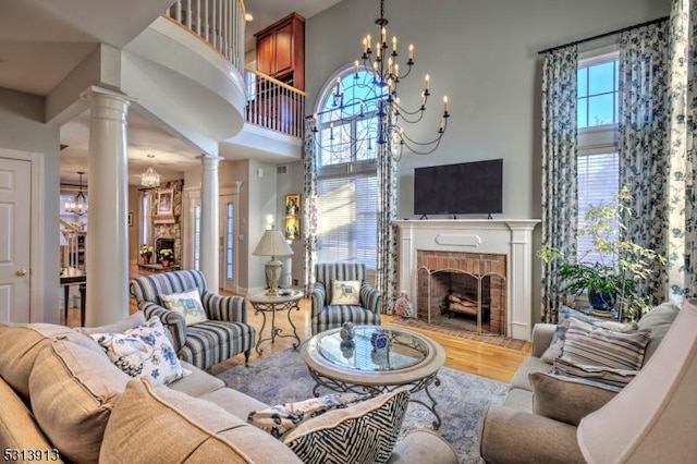 living room with hardwood / wood-style flooring, ornate columns, a notable chandelier, and a fireplace