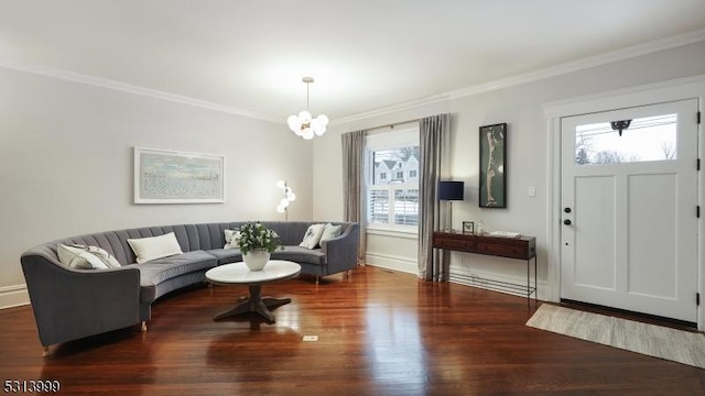 living room with dark wood-type flooring, ornamental molding, and a chandelier