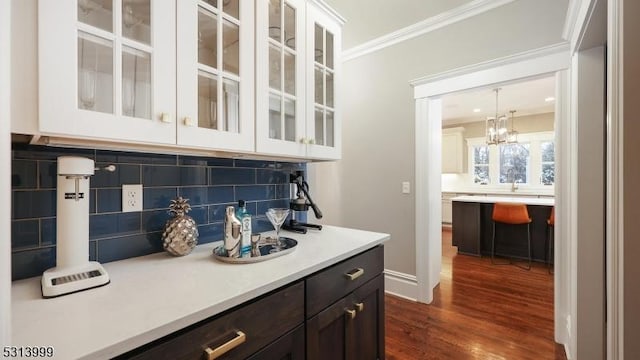 bar with white cabinets, tasteful backsplash, hanging light fixtures, ornamental molding, and dark brown cabinets