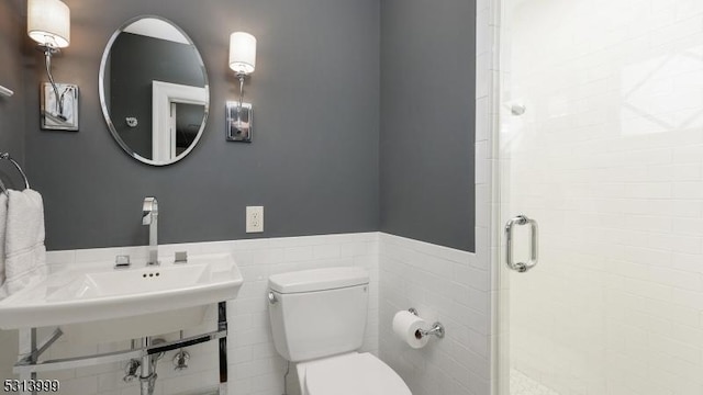 bathroom featuring sink, toilet, tile walls, and an enclosed shower