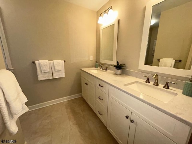 bathroom with double vanity, baseboards, and a sink