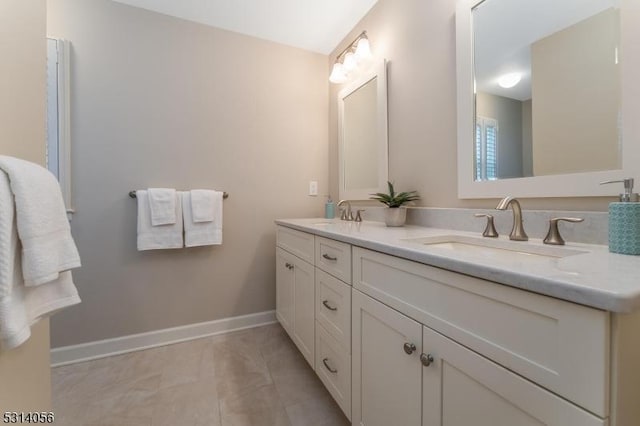 bathroom featuring double vanity, tile patterned flooring, baseboards, and a sink