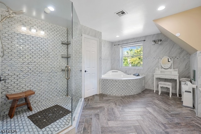 bathroom with shower with separate bathtub, lofted ceiling, and tile walls