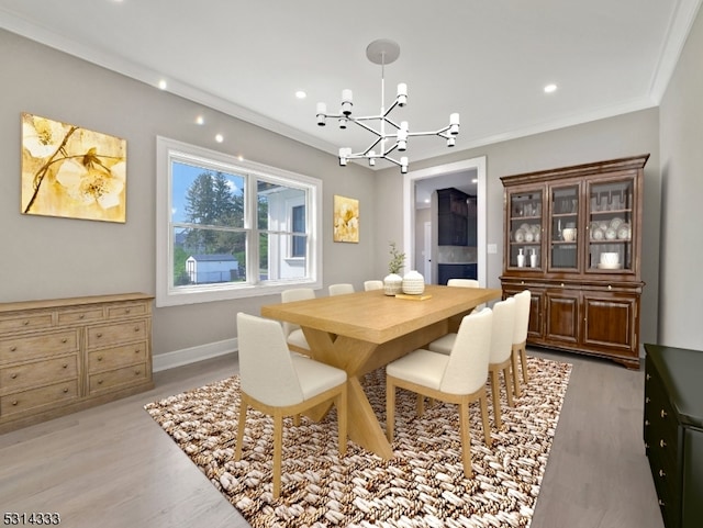 dining room with light hardwood / wood-style floors, ornamental molding, and a notable chandelier