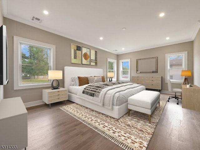 bedroom with ornamental molding, multiple windows, and hardwood / wood-style flooring