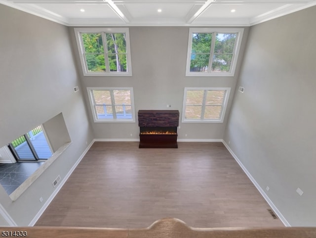 unfurnished living room featuring a wealth of natural light, coffered ceiling, and hardwood / wood-style flooring