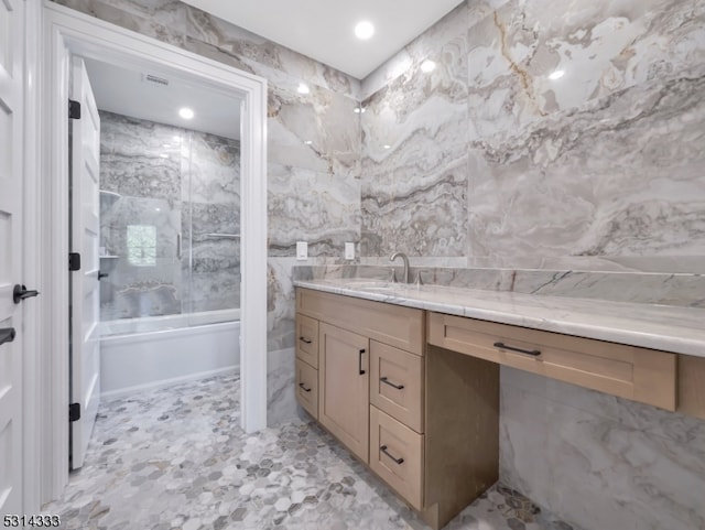 bathroom featuring tile walls, tiled shower / bath, and vanity