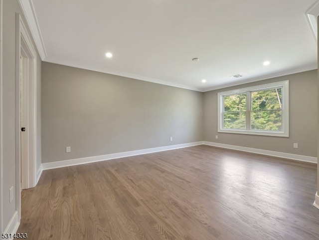 empty room featuring light wood-type flooring and crown molding