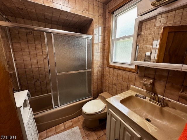 full bathroom featuring enclosed tub / shower combo, vanity, tile patterned floors, tile walls, and toilet