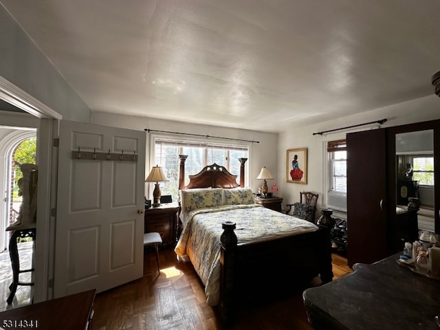 bedroom with multiple windows, access to outside, and hardwood / wood-style flooring