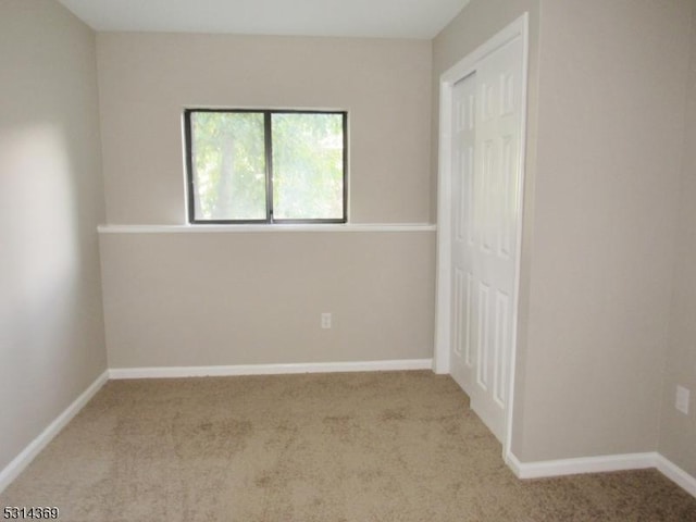 unfurnished bedroom with light colored carpet and a closet