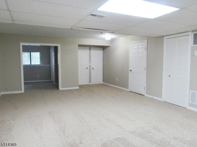 unfurnished bedroom with a paneled ceiling, carpet floors, and two closets