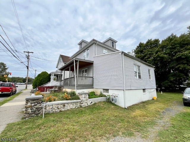 view of property exterior with a yard and a porch