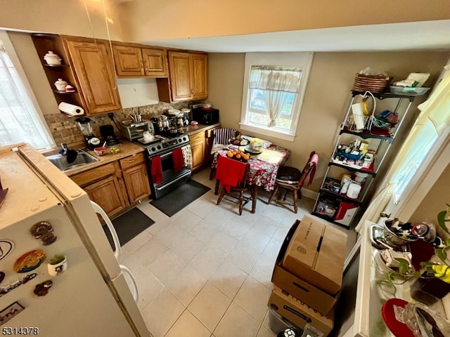 kitchen featuring stainless steel stove, sink, backsplash, and white fridge