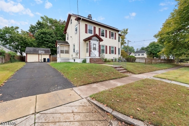 view of front of property with a garage, an outbuilding, and a front lawn